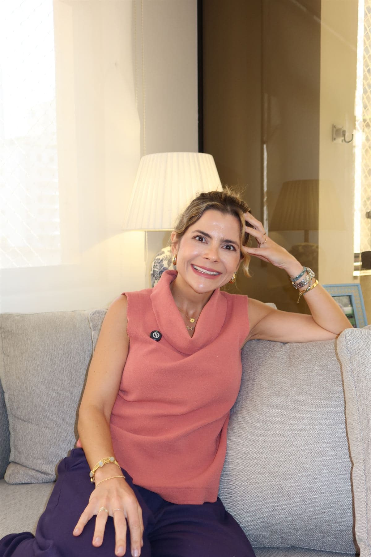 Paula Braga sorrindo, sentada no sofá do consultório