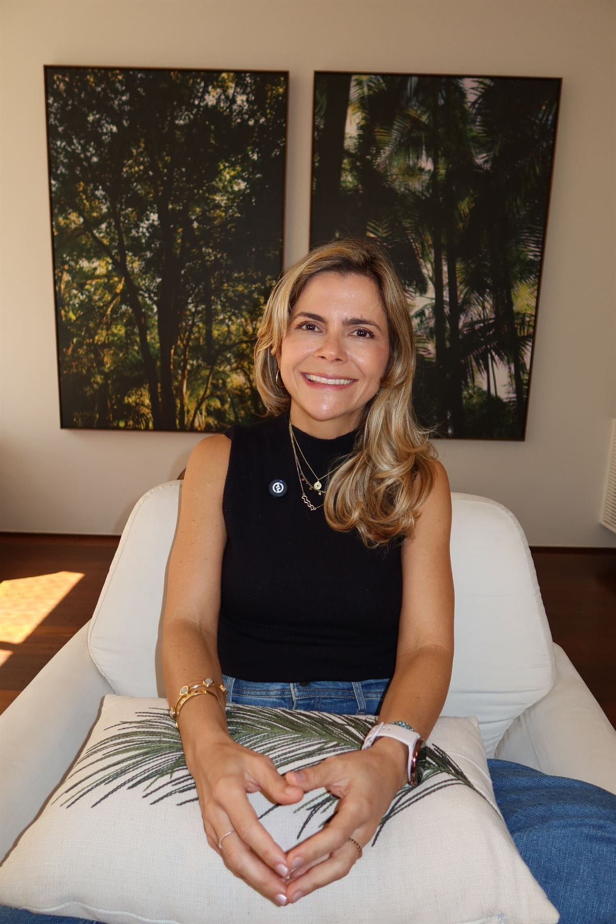 Paula Braga em poltrona clara, com fotografias de árvores ao fundo